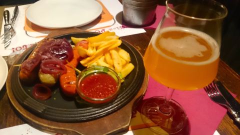 Porção de salsichas  mistas com cebola roxa caramelizada e fritas, no Pub da cervejaria Baladin